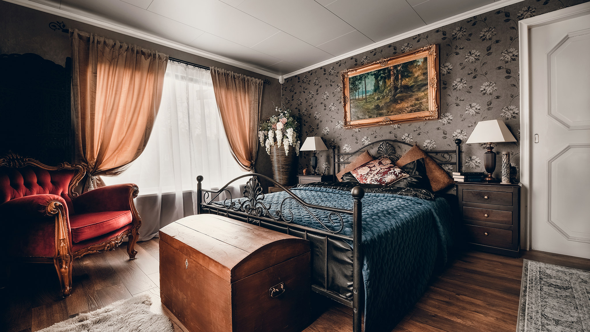 Nydelig rom i gammel stil med en gammel seng, blomster og bilder på veggen