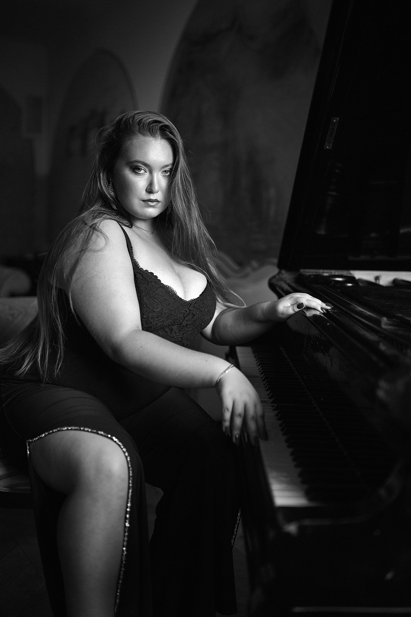 En kvinne med langt blondt hår sitter i en vakker svart kjole ved pianoet